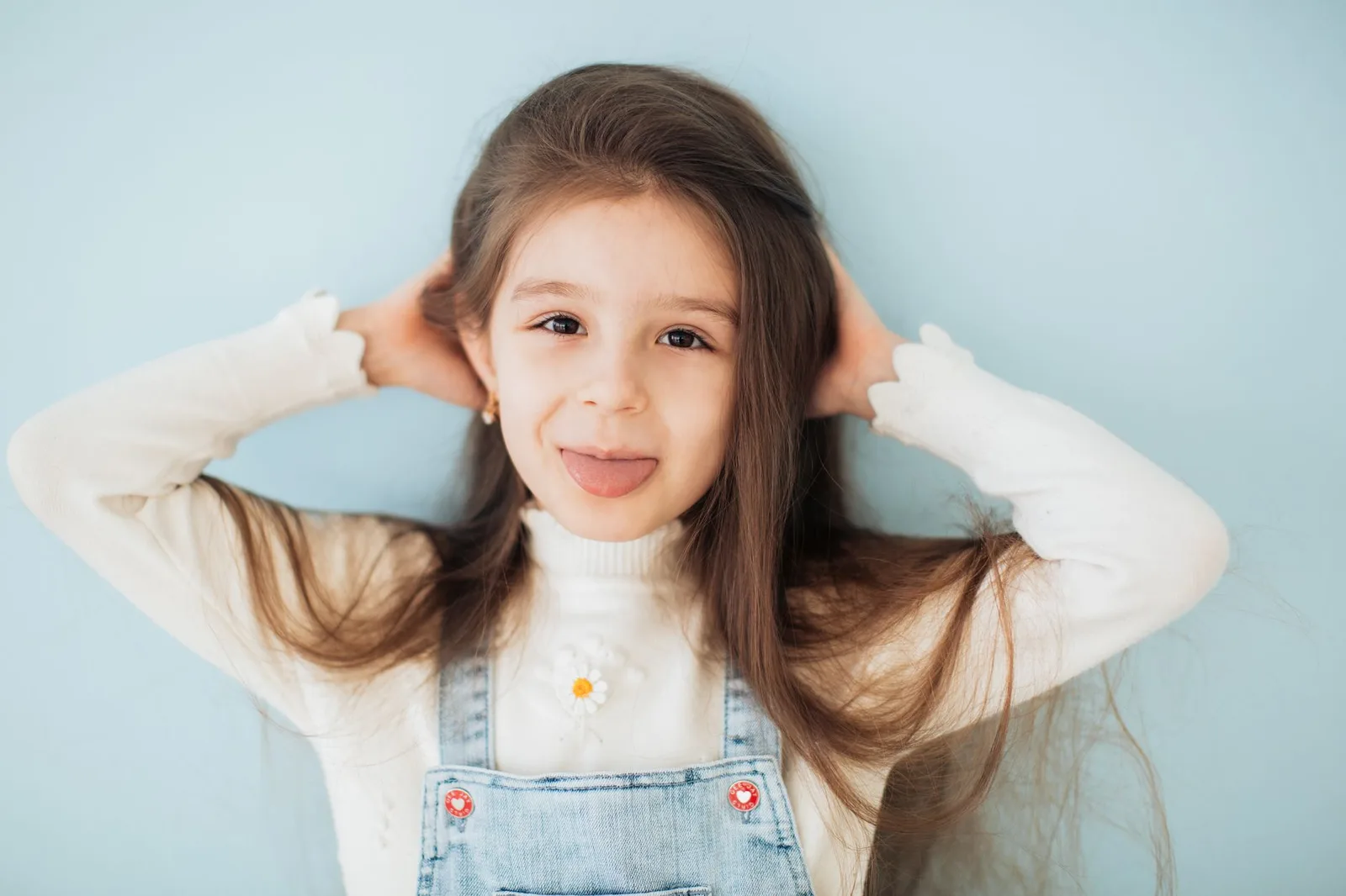 Cute child playfully sticking out tongue against a blue background.