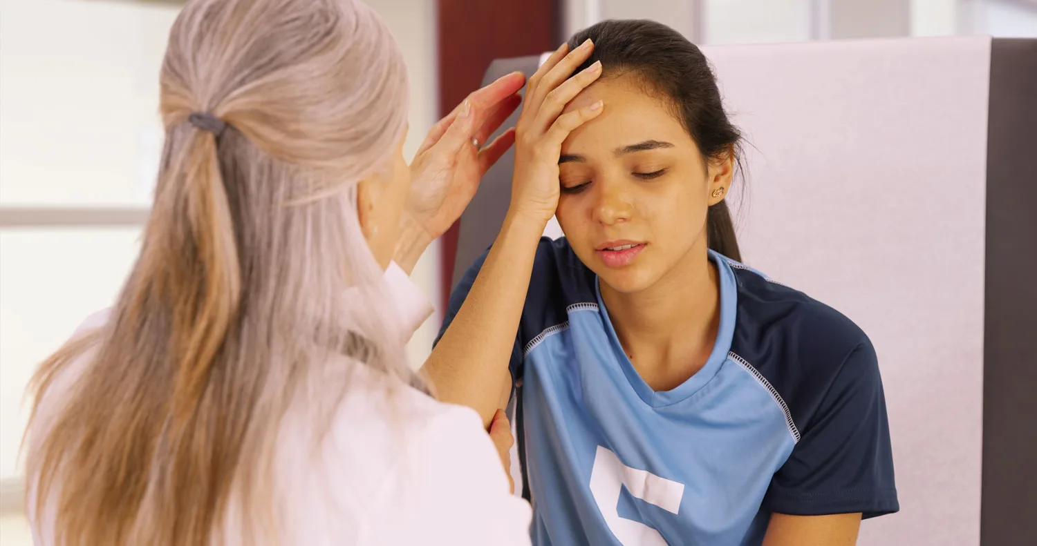 Healthcare provider examining young patient's head during pediatric medical appointment.