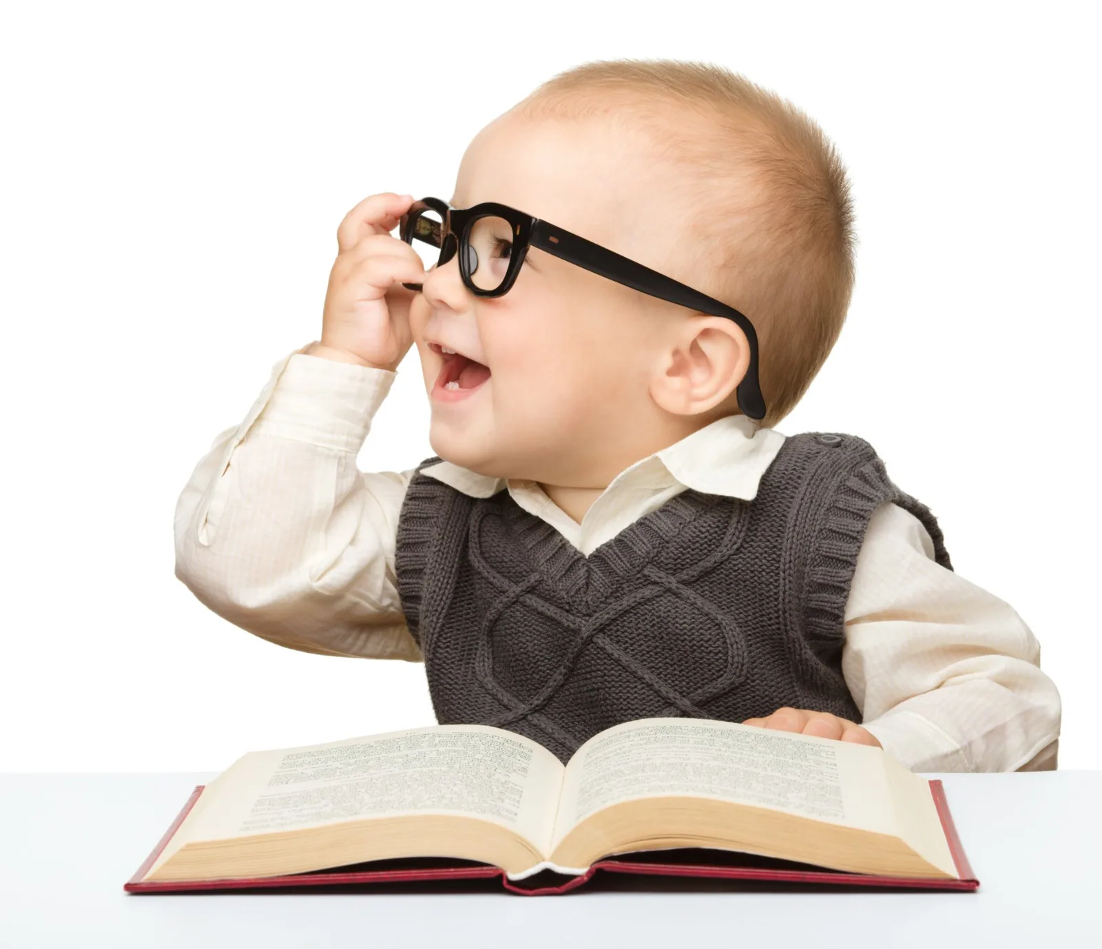 Young child wearing oversized glasses sitting at open book, looking surprised.