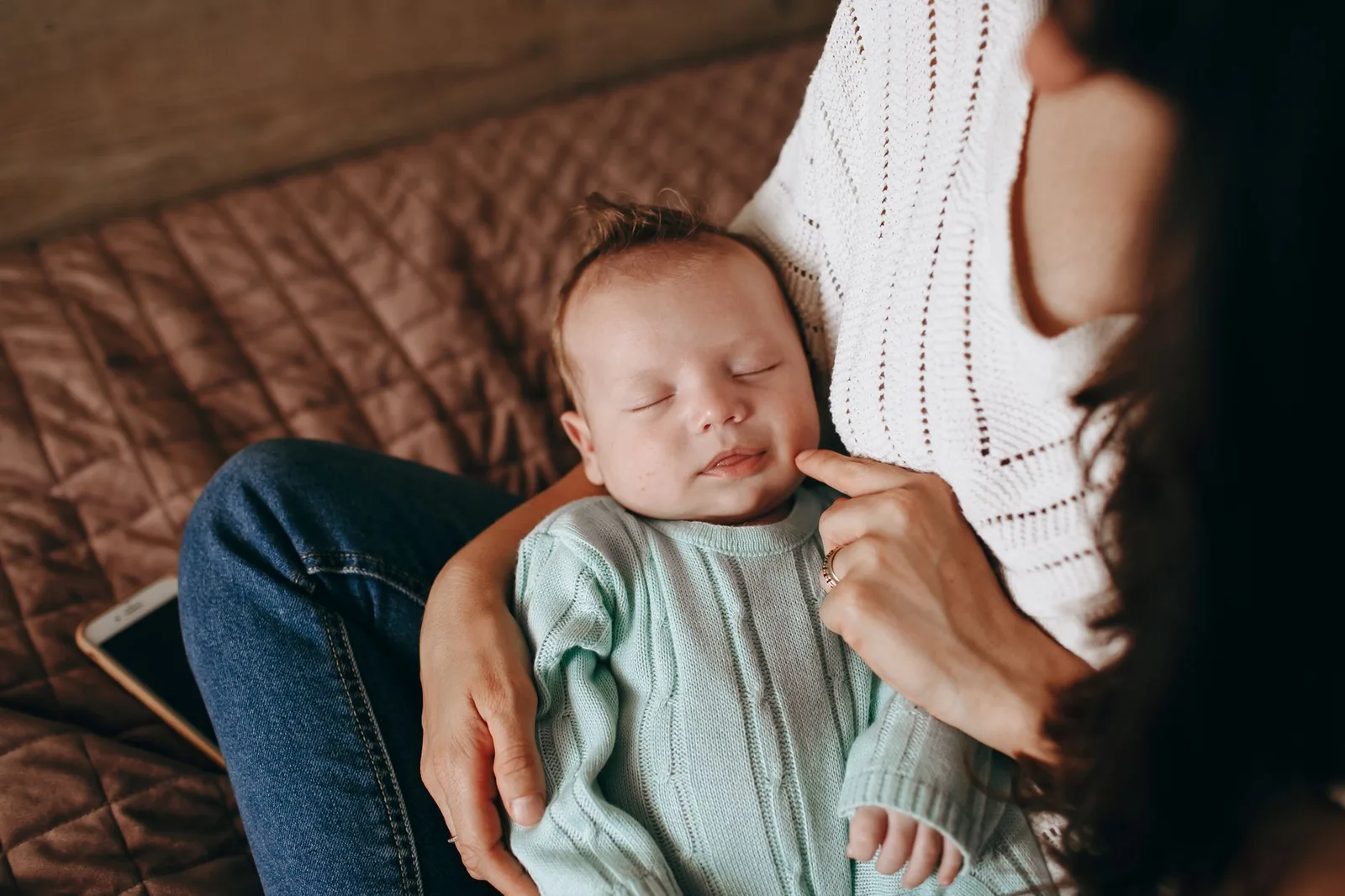 A serene photograph of a mother cradling her sleeping baby indoors, capturing warmth and love.