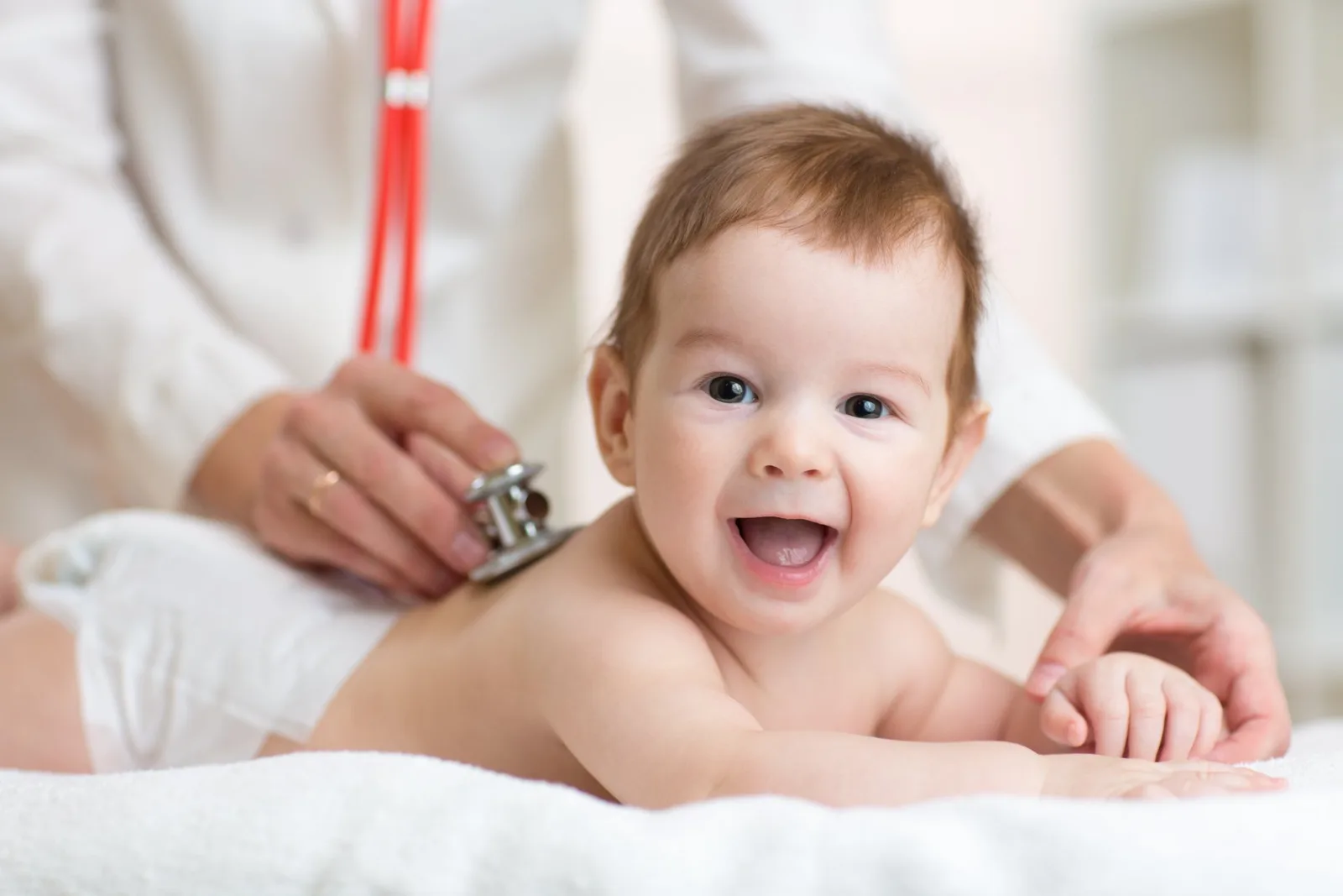 Infant receiving stethoscope examination from healthcare provider during medical checkup.
