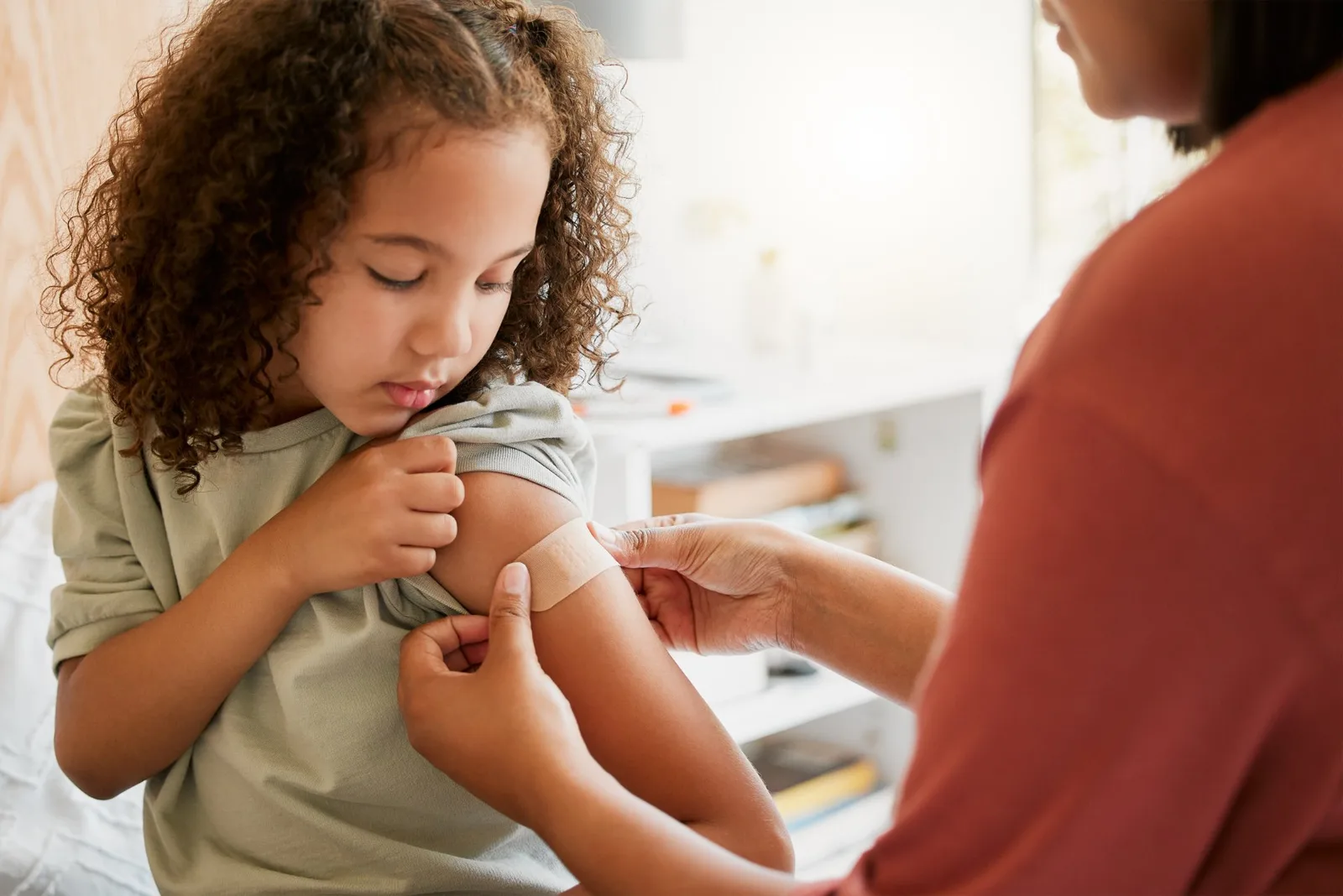 Adult applying bandage to child's arm during medical examination.