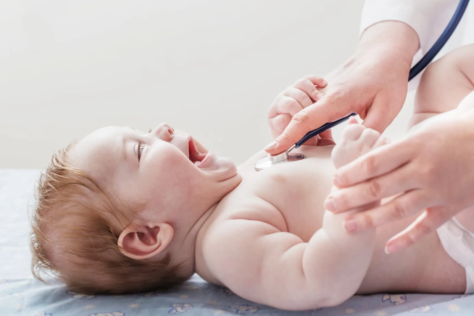 Doctor using stethoscope to examine infant's chest during pediatric checkup.