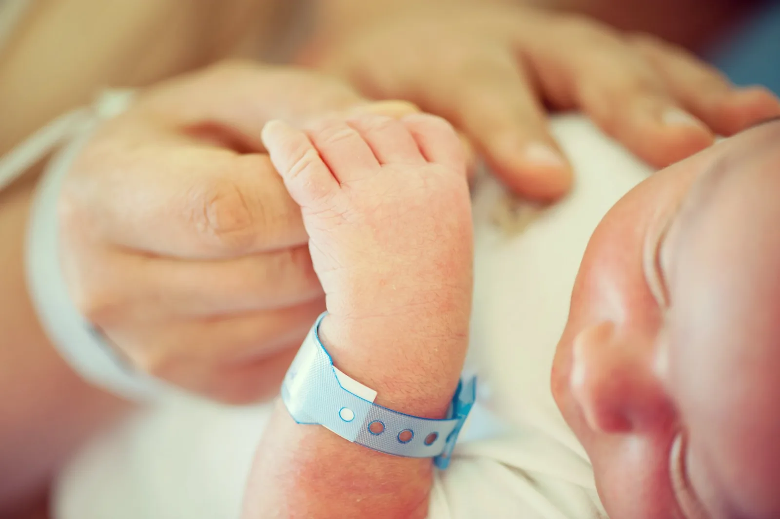 Newborn baby wearing hospital identification bracelet on wrist.